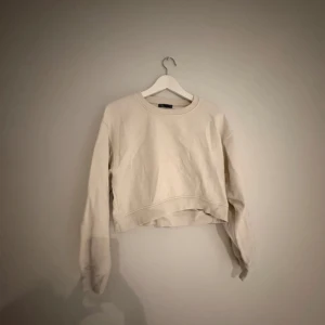 Beige croppad sweatshirt från Zara - Säljer en beige croppad sweatshirt från Zara i mjuk bomull. Tröjan har rund halsringning, långa ärmar och ribbade muddar. Enkel och clean design som är lätt att matcha med jeans eller kjol.