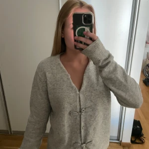 Grå kofta med rosettknäppning - Mysig grå kofta med fina rosett knappar framtill! Storlek M men passar mig som använder xs/s!!🥰