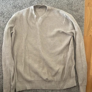 Beige stickad tröja  - Säljer en beige stickad tröja från C i storlek M. Tröjan har rund halsringning, ribbad struktur och långa ärmar. Perfekt för lager-på-lager och chill dagar. Enkel och stilren design som funkar till det mesta.