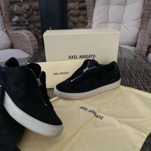 Axel arigato clean 90 zip - svarta - 37 -  Axel Arigato Clean 90 Zip – Svarta (Limited Edition) 📏 Storlek: 37 💸 Pris: 1100 kr 🛍️ Nypris: ca 2800 kr  ✨ Skick: Extremt fint skick! Endast använda ett fåtal gånger och ser praktiskt taget nya ut. Inga skador, repor eller slitage – både ovandel, sula och detaljer är i toppskick. Levereras med originalkartong och allt som följde med vid köpet.  🔒 Limited Edition: Denna modell är superlimiterad och går inte längre att köpa i butik.