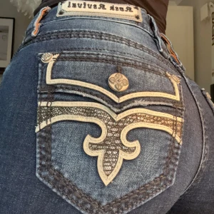 Rock Revivial Jeans 🎸😍😍 - Väldigt snygga Rock Revival Jeans 😍✨ Low/Mid Waist, Boot Cut, Mörkblå färg med inslag av ljusare partier på benen. Storlek 26.  Midjemått: Ca 36/37 cm  Innerbenslängd: Ca 82 cm Prislappen är kvar, alltså aldrig använda! Nypriset låg på 2399 kr 💫