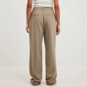 Beiga / bruna kostymbyxor  - Hej! Säljer ett par beiga / bruna kostymbyxor med raka ben och pressveck. Byxorna har hög midja och är raka i passformen. Från NAKD i stl S🤎