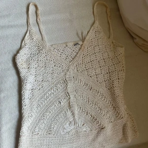 Vit Sommar linnetopp - Superfin vit virkad linnetopp från Events med smala axelband och v-ringning. Toppen har ett unikt mönster med virkade detaljer och är perfekt för varma dagar. Lätt och luftig känsla, passar snyggt till både jeans och kjol. Har några fläckar men syns inte när man sätter på den 