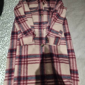 Rutig overshirt i ullmix, beige/röd - Snygg lång overshirt i beige med rött och blått rutmönster. Jackan har knappar framtill, två bröstfickor och långa ärmar. Perfekt för lager-på-lager och ger en chill vibe till din outfit.