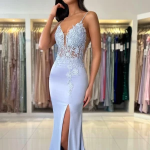 Ljusblå långklänning med spetsdetaljer - Superfin ljusblå långklänning med tunna axelband, djup v-ringning och blommiga spetsdetaljer upptill. Klänningen har en figurnära passform, hög slits framtill och är gjord i ett glansigt material som ger en lyxig känsla. Perfekt för bal eller fest! Klänningen är köpt från dressroom linne för 4500kr. 