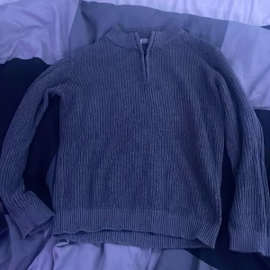 Grå ribbstickad tröja från Primark - Mysig grå ribbstickad tröja från Primark med lång ärm och halv dragkedja vid halsen. Perfekt för kyliga dagar och enkel att matcha med jeans eller kjol. Klassisk modell med högre krage och relaxed fit.