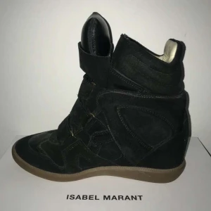 Svarta wedge sneakers Isabel Marant - Coola svarta wedge sneakers från Isabel Marant med högt skaft, breda kardborreband och beige innersida. Skorna har en blandning av mocka och skinn, samt en platt gummisula i kontrasterande färg. Perfekta för dig som vill ha en edgy och trendig look.