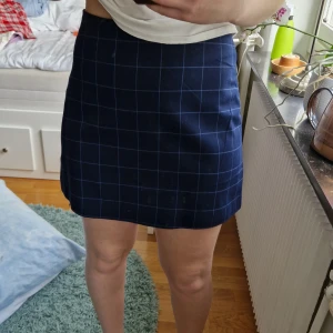 Mörkblå kjol - Mörkblå kjol med lätt, vitt rutigt mönster. Dragkedja baktill och en rätt rund form