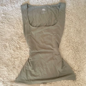 Ljusgrön linnetopp från 157 - Superskön ljusgrön linnetopp från 157 med breda axelband och fyrkantig ringning. Sitter tight och har en enkel, clean look som passar perfekt till jeans eller kjol. Mjuk bomullskänsla och stretchigt material för en bekväm passform.