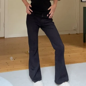 Svarta bootcut byxor med låg midja - Säljer ett par svarta byxor med bootcut och låg midja. Byxorna har breda hällor, dubbla knappar i midjan och en snygg, figurnära passform upptill som släpper ut vid benen. Perfekta för dig som gillar en klassisk men trendig look.