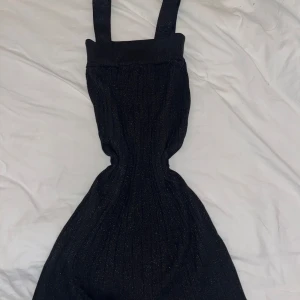 Svart glittrig klänning med breda axelband från H&M - Supersnygg svart klänning från H&M med glittriga detaljer och breda axelband. Klänningen har ribbad struktur, perfekt för att sticka ut lite extra. Säljes i storlek XS.