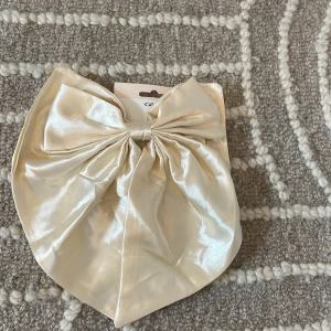 Krämfärgat stor rosett från Glitter -  Super sött rosett från glitter. Ser kanske konstig ut på bild men tror den lägger sig super snyggt när man har på sig den. Kostar egentligen 149kr 