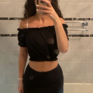 Svart croppad topp från Gina Tricot - Säljer en svart croppad topp från Gina Tricot med puffärmar och resår vid ärmslut, halsringning och nederkant. Toppen har en söt volangdetalj längs kanterna och är perfekt för en trendig look. Oanvänd, passar s också