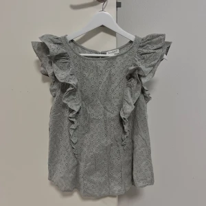 Ljusgrön blus med volang - Ljusgrön blus med broderade blommor, volangdetaljer längs axlar och fram. Aldrig använd💕