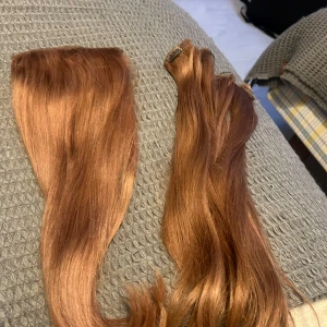 Löshår clip-on i kopparbrun nyans - Säljer clip-on löshår i en snygg kopparbrun färg. Håret är rakt och glansigt, perfekt för att ge extra längd och volym. Passar dig som vill ha en naturlig look med enkel applicering.