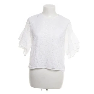 Vit spetsblus med volangärm från Zara Woman - Säljer en vit blus från Zara Woman med vackert spetsmönster och volangärmar. Blusen har rund halsringning och är tillverkad i ett lätt och luftigt material, perfekt för vår och sommar. Prister går att diskutera 💕