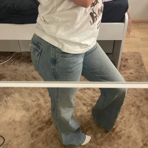 Ljusblå bootcut jeans - Säljer ett par ljusblå bootcut jeans med klassisk femficksdesign och låg midja. Jeansen har en lätt utsvängd passform nertill och är tillverkade i denim. Perfekta för dig som gillar en avslappnad och trendig stil.