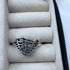 Silverfärgad ring med nätmönster - Unik silverfärgad ring med ett öppet nätmönster som påminner om ett spindelnät. Perfekt för dig som gillar statement-smycken med en cool och modern känsla.