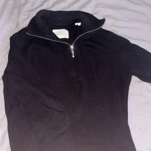 Svart stickad tröja med dragkedja från Jack & Jones - Säljer en svart stickad tröja från Jack & Jones med hög krage och dragkedja framtill. Tröjan har lång ärm och är ribbstickad vilket ger en snygg och stilrena look. Knappt använd. Mvh Vidar 