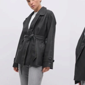 Svart skinnjacka med bälte från Gina tricot  - Snygg svart/grön skinnjacka från Gina med bälte i midjan. Köpte för 899kr i Mars så den är väldigt ny. Tänkte sälja för 700 men kom med prisförslag! 