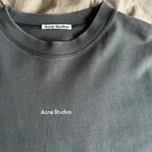 Acne tshirt  - Säljer denna supersnygga tshirt från Acne Studios. Använd men i ett superfint skick. I en grå/svart färg. Basic lite boxigare t-shirt med text över bröstet. Funkar på killar som tjejer. Storlek XS. Nypris 2500kr. Säljer för 800kr.