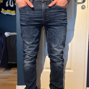 Mörkblå jeans från Blend - Säljer ett par mörkblå jeans från Blend med klassisk femficksdesign och snygga kontrastsömmar. Jeansen har normal passform och raka ben, perfekt för en stilren vardagslook. Gylf med dragkedja och knapp. Storleken är oklar men sitter bra på mig som är 190cm och har vanligtvis M-L.
