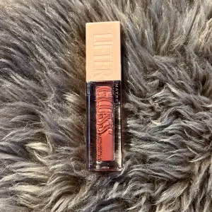 Har aldrig använt❤️ - Säljer ett Maybelline Lifter Gloss i färgen 004 Silk. Det är ett läppglans i en nude-rosa nyans med glansig finish och stor applikator. Perfekt för att ge läpparna en fylligare look och extra lyster.