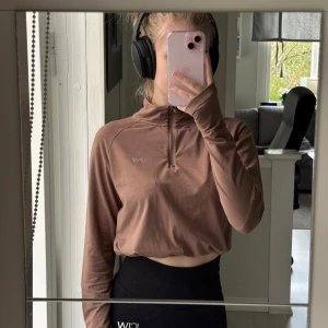 ICANIWILL croppad träningströja justerbar - En brun croppad långärmad träningströja från ICANIWILL med halv dragkedja framtill och justerbar dragsko i nederkant. Perfekt för gymmet eller löprundan. Mjuk och stretchig i materialet.  Nyskick! Nypris 500kr 