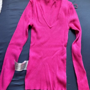 Rosa  v-ringad tröja - Säljer en snygg rosa ribbad tröja med v-ringning och långa ärmar. Tröjan har en tight passform och är perfekt (säljer den pågrund av de är inte min färg)