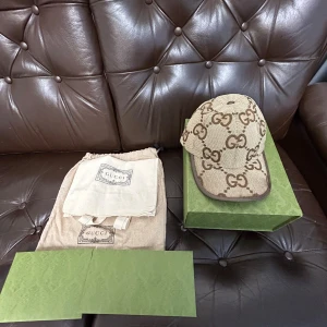 Beige GG Supreme keps från Gucci - Säljer en beige keps från Gucci med det klassiska GG Supreme-mönstret i Bech,perfekt för dig som gillar exklusiva accessoarer. Storlek s                    Priset kan diskuteras.