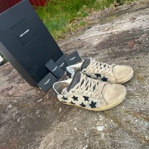 Saint Laurent skor med stjärnor - Säljer nu ett per riktigt feta saint Laurent skor i väldigt populära/eftertraktad modell, tyvärr är skorna inte i sit bästa skick därav de billiga priset, går att fräscha upp en hel del men inget jag tyvärr har tid med så säljer dom istället billigt, storlek 41 men sitter mer som 42+, allt og medföljer förutom dustbag, sjävklart förekommer defekter som syns på bilderna🌟