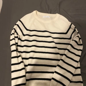 Vit och svart randig stickad tröja - Säljer en vit stickad tröja från primark med svarta horisontella ränder. Tröjan har rund halsringning och långa ärmar. Perfekt för en stilren och klassisk look.