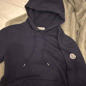 Marine blå moncler hoodie - Säljer en marine blå hoodie från Moncler den är bokstavligen använd 2 gånger, den ser lite smutsig ut men de är bara för att den legat i garderoben en tvätt så är den som ny. Storlek S. Sitter jätte bra och är skön till sommarkvällar och nu till hösten. Skriv gärna vid minsta fundering. ;)