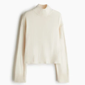 Vit stickad polotröja - Säljer en stilren vit stickad polotröja med ribbade detaljer vid hals, ärmslut och nederkant. Tröjan har en hög krage och lång ärm, perfekt för lager-på-lager under kyliga dagar. Enkel att matcha med både jeans och kjol.