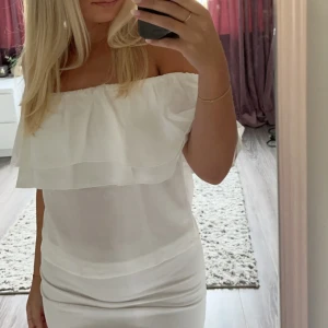 Vit offshoulder topp - Säljer en vit offshoulder topp med volang upptill. Toppen är tight och har en enkel, stilren design som passar perfekt till sommarens tillfällen. Materialet känns lätt och luftigt.