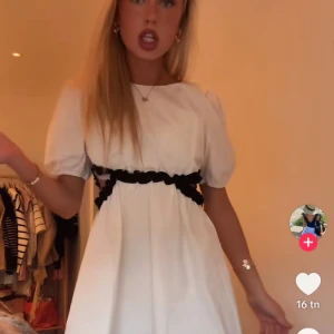 Vit klänning - Superfin vit kortklänning med puffärmar och svarta volangdetaljer runt midjan. Helt oanvänd, lapp kvar! Passar xs-S