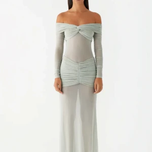 Ljusgrå offshoulder långklänning - Supersnygg ljusgrå långklänning med offshoulder och långa ärmar. Klänningen har draperade detaljer över byst och höfter, samt en figurnära passform. Tunt, lätt transparent material som ger en modern och elegant look.