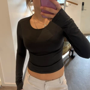 Mörkgrå  croppad långärmad topp - En mörkgrå, croppad långärmad topp med rund halsringning. Använd ett par enstaka gånger. Storlek S/XS