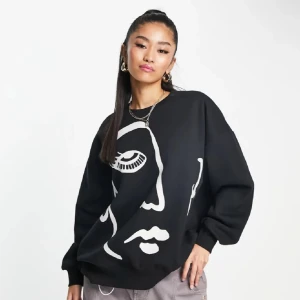Svart oversized sweatshirt med ansiktsmotiv - En slutsåld svart oversized sweatshirt i storlek M! med ett stort vitt grafiskt ansiktsmotiv framtill. Perfekt för en cool och avslappnad stil.