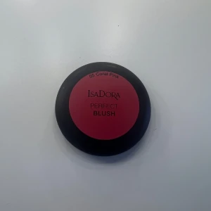 IsaDora Perfect Blush Coral Pink - IsaDora Perfect Blush i färgen 05 Coral Pink. En puderrouge i en snygg korallrosa nyans, perfekt för att ge kinderna en fräsch och naturlig glow. Kommer i en rund svart dosa med spegel i locket, smidig att ha med i väskan.
