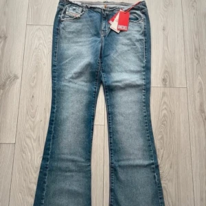 Blå bootcut jeans Diesel - Snygga blå jeans från Diesel med bootcut passform.  Jeansen har en lätt tvättad look och är tillverkade i slitstarkt denim.  Byxorna har en rå kant upptill som du kan se på bilden. Helt nya med prislappen på!! Stl 29W 34L