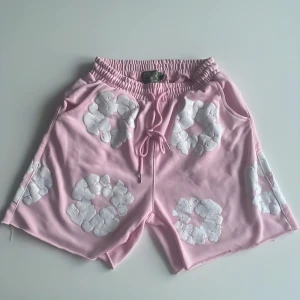 Rosa shorts från Denim Tears - Rosa Denim Tears shorts  Eftertraktade shorts från Denim Tears i en snygg rosa nyans. Tillverkade i 100 % bomull – sköna, slitstarka och perfekta för både vardag och sommarfit. Mycket bra skick. Storlek: medium.