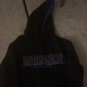 Svart hoodie från Hoodrich - Säljer en svart hoodie från Hoodrich med blå detaljer och text på framsidan, baksidan och små detaljer, säljer för jag inte använder den