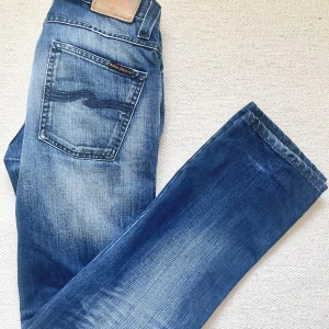 Nudie jeans Slim Jim - Säljer ett par blå sällsynta Nudie Jeans i bra skick. De har slitningar och hål på knäna. (om man inte diggar hålen kan man laga dem gratis hos nudie) sitter slim med straight leg. Stl. W28 L32