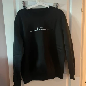 Svart sweatshirt med texten 'whatever' - Svart sweatshirt med vit broderad text 'whatever' på bröstet. Tröjan har rund halsringning och långa ärmar med ribbade muddar. Enkel och stilren design som passar perfekt till jeans eller mjukisbyxor.