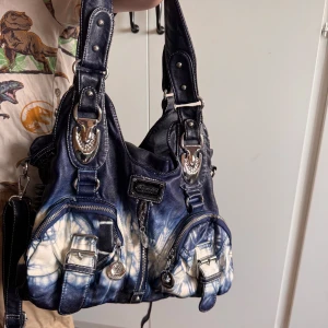 Blå-vit axelväska från Kumixi Fashion - En snygg axelväska från Kumixi Fashion som använts ett fåtal gånger, har två rymliga delar i väskan med varsin separat dragkedja.