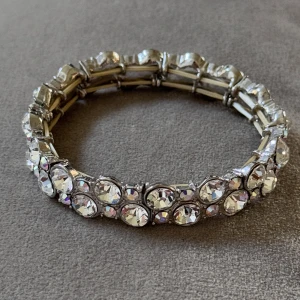 Glittrigt armband med stora stenar - Snyggt armband i silverfärg med stora, runda glittriga stenar som fångar ljuset. Armbandet har elastisk design och ger en riktigt lyxig känsla. Perfekt för dig som vill sticka ut och addera extra bling till din look.