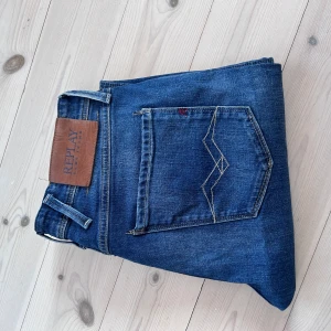 Replay Anbass blåa - Snygga blå Replay Anbass jeans i storlek 29W/32L. Jeansen har en ganska rak passform. Coola detaljer med fina kontrastsömmar och rött R. Är lite naturligt stretch vilket gör dem sköna att använda. Skicket är bra, är nytvättade så ser lite skrynkliga ut. 