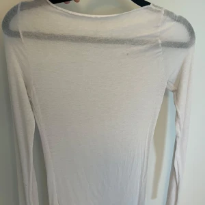 Vit långärmad tunn tröja intimissmi - Intimissmi tröja. Superenkel och tunn vit långärmad tröja med rund hals. Sitter tight mot kroppen och är perfekt att ha som basplagg eller under en hoodie. Materialet känns mjukt och lätt, vilket gör den skön att bära hela dagen.