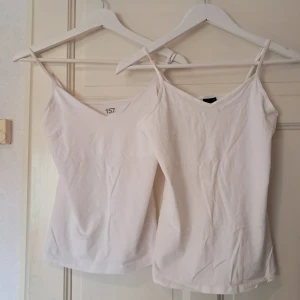 2 st vita linnen från Gina Tricot & lager 157 - Två stilrena vita linnen med smala axelband, ett från Gina Tricot i storlek M och ett från lager 157 i storlek S. Båda har v-ringad hals. Perfekta att matcha med jeans eller kjol för en clean look.